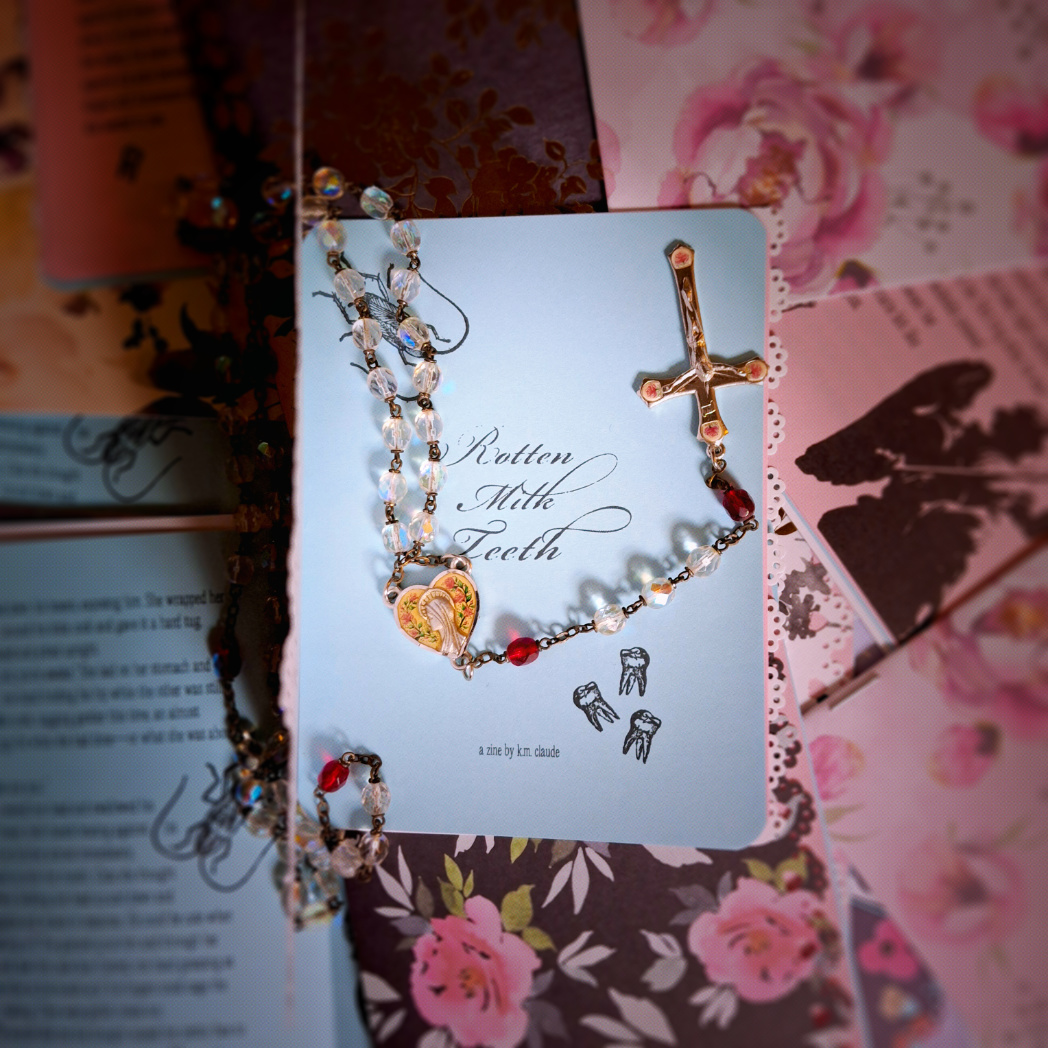 zine titled rotten milk teeth with rosary atop pile of other zines with varied covers