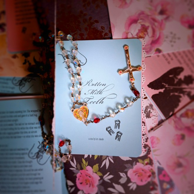 zine titled rotten milk teeth with rosary atop pile of other zines with varied covers